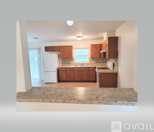 A kitchen with brown cabinets and a marble countertop.