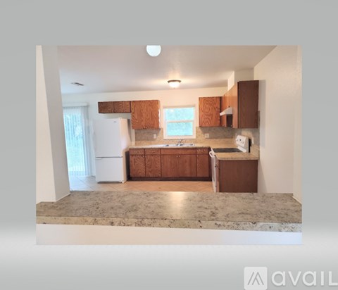 A kitchen with brown cabinets and a marble countertop.