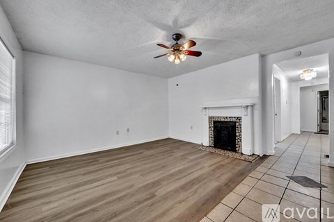 A living room with a fireplace and a ceiling fan.
