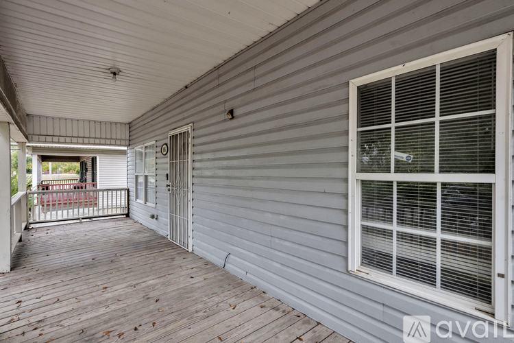 A porch with a white railing and a window with blinds.