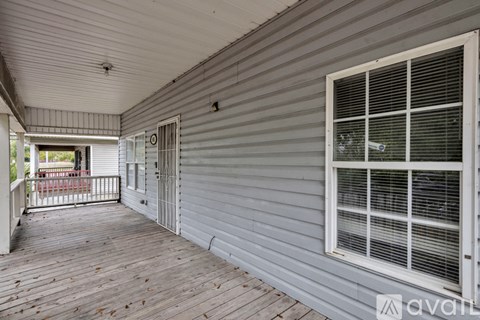 A porch with a white railing and a window with blinds.