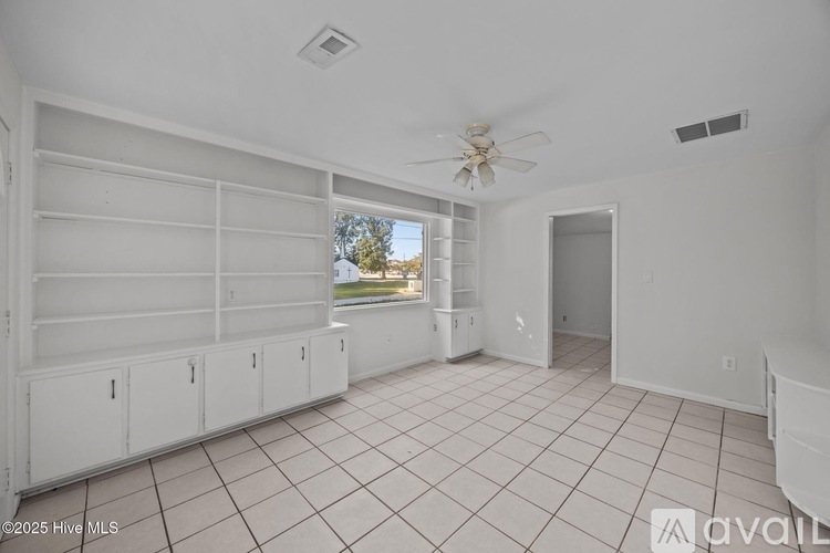 A spacious room with a ceiling fan and tiled flooring.