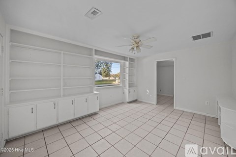 A spacious room with a ceiling fan and tiled flooring.