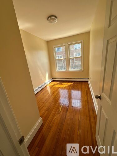 A hallway with wooden floors and a window with a view of a building outside.
