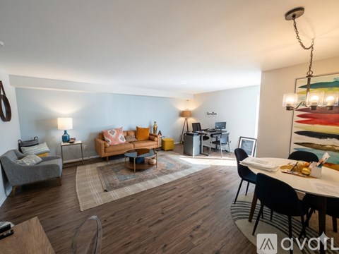 A living room with a grey sofa, a yellow couch, a wooden floor, and a dining table with chairs.