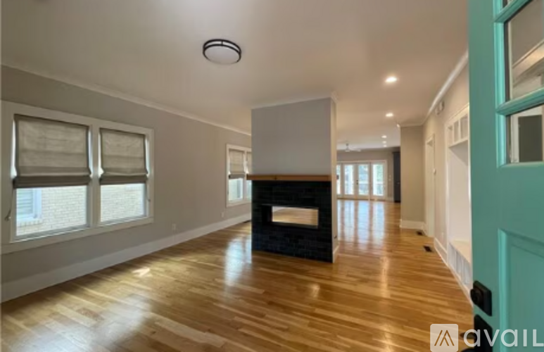 A spacious room with a fireplace and wooden floors.
