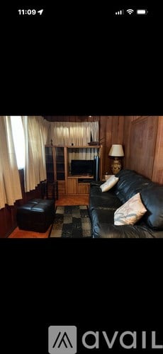 A living room with a black leather couch and a wooden cabinet.