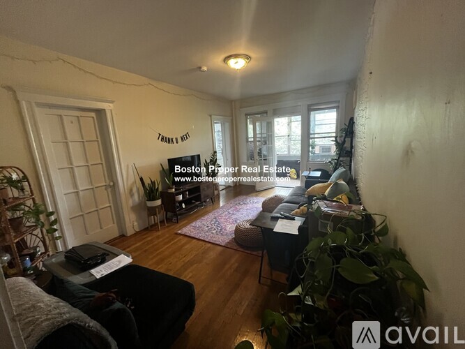 A living room with a couch, a chair, a table, and a sign that says "Boston Premier Real Estate" on the wall.