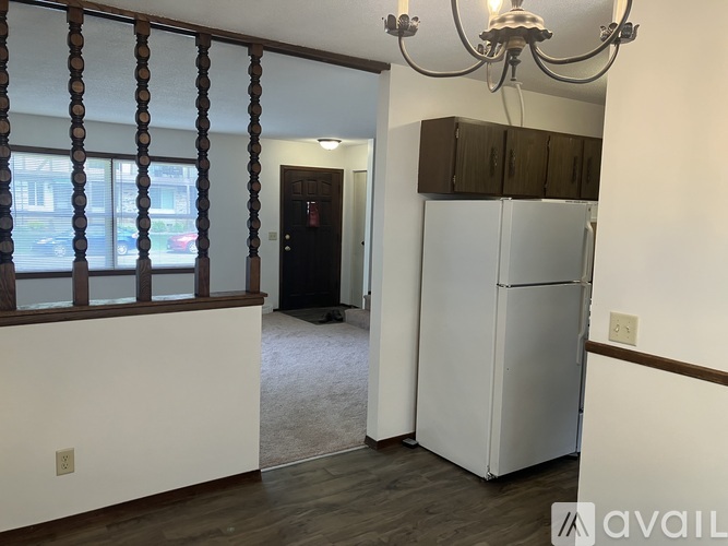 A room with a white fridge and a chandelier.