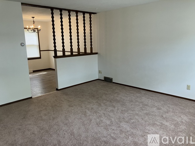 A room with a carpeted floor and a window with a wooden frame.