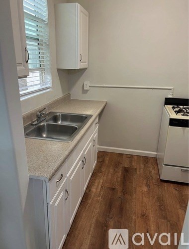 A kitchen with white cabinets and a wooden floor.