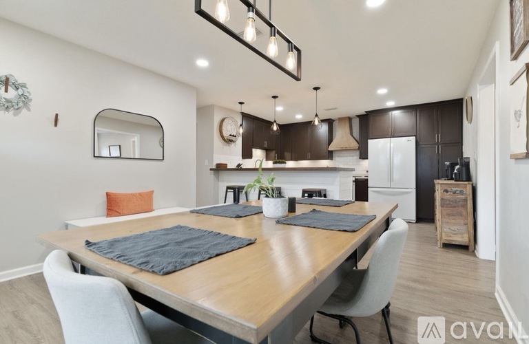 A modern kitchen with a wooden dining table and grey chairs.