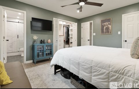 A bedroom with a large bed and a flat screen TV mounted on the wall.