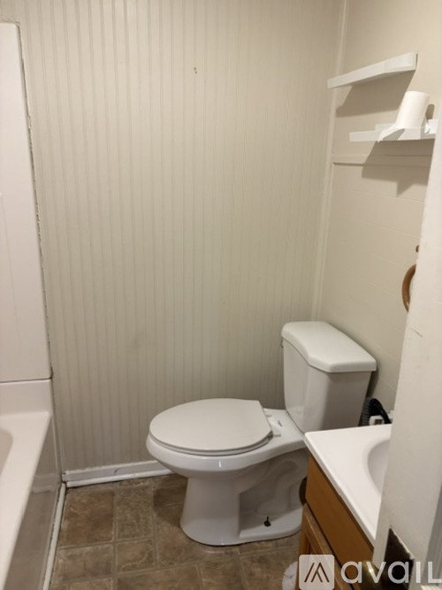 A white toilet sits in a bathroom with a white towel hanging on the wall.