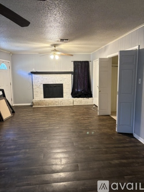 A living room with a fireplace and a ceiling fan.