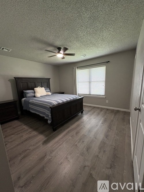 A bedroom with a bed, dresser, and window.
