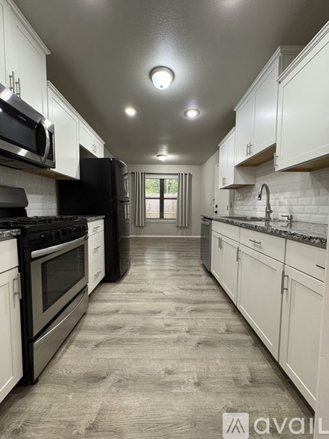 A kitchen with white cabinets and black appliances.