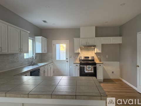 A kitchen with a tile floor and white cabinets.