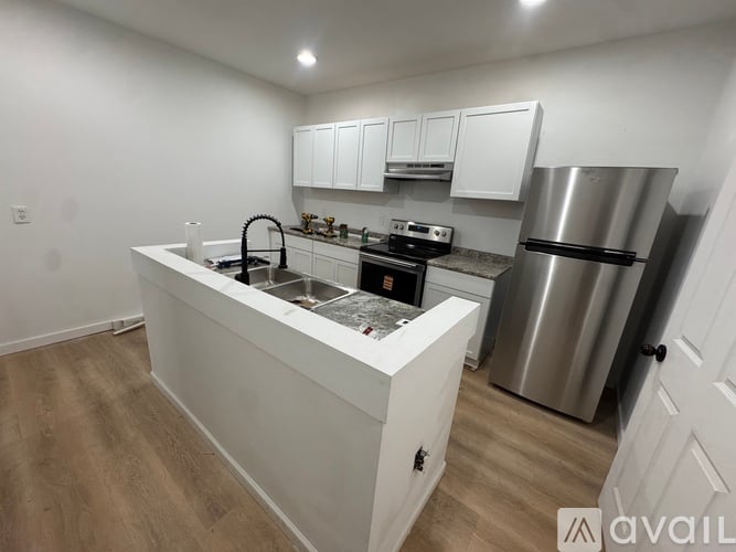 A kitchen with white cabinets and a stainless steel refrigerator.