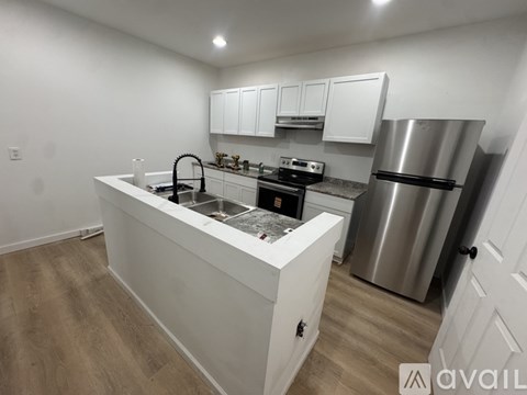 A kitchen with white cabinets and a stainless steel refrigerator.