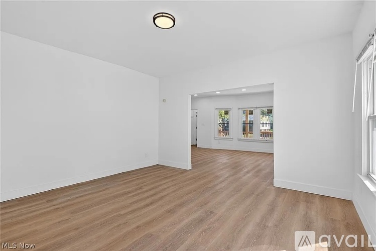 A spacious room with wooden flooring and white walls.