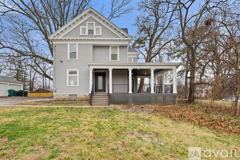 A two-story house with a front porch and a fenced yard.
