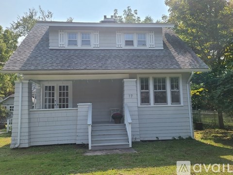 A small white house with a porch and a number 17 on the door.