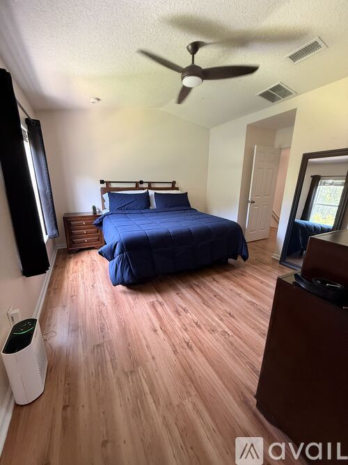 A bedroom with a bed, dresser, and ceiling fan.