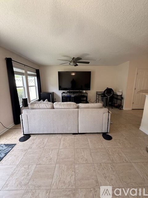 A living room with a white couch and a flat screen TV.