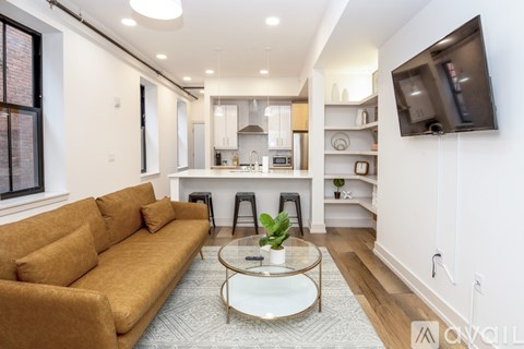 A living room with a brown couch and a glass coffee table.