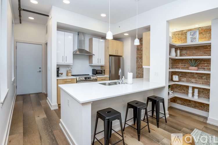 A kitchen with white cabinets and a white island with three black stools.