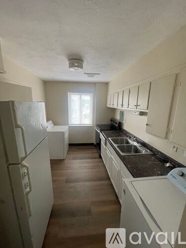A kitchen with white appliances and wooden floors.