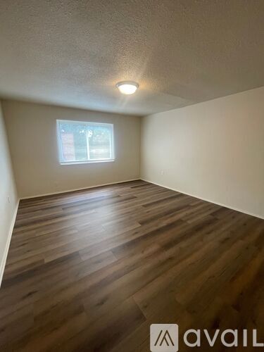 A room with wooden flooring and a window.