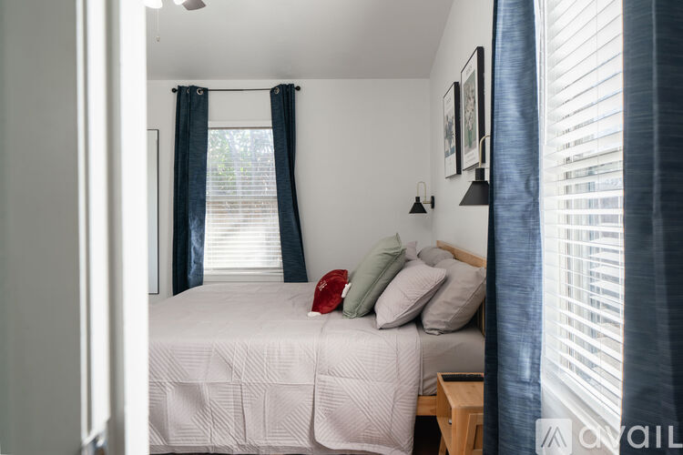 A bedroom with a bed, pillows, and a window with curtains.