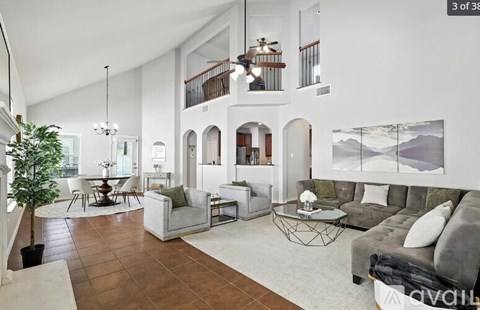 A living room with a couch, a chair, a coffee table, a potted plant, and a painting on the wall.