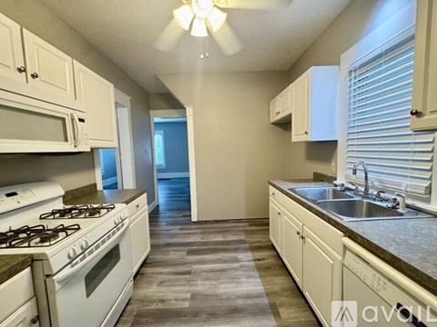 A kitchen with white cabinets and a stove top oven.