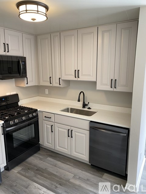 A kitchen with white cabinets and a black stove top oven.