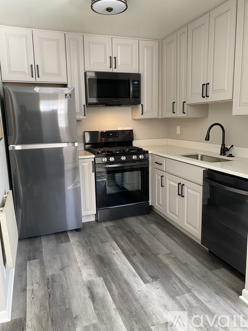 A kitchen with a stainless steel refrigerator, black microwave, and a black oven.