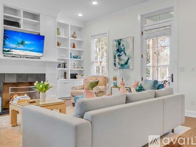 A living room with a grey couch, a fireplace, and a TV on the wall.