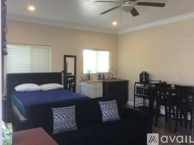 A bedroom with a bed, chair, and a fan.