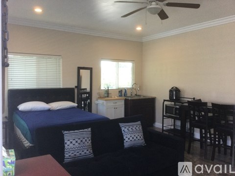 A bedroom with a bed, chair, and a fan.