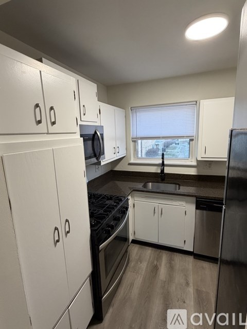 A kitchen with white cabinets and black appliances.