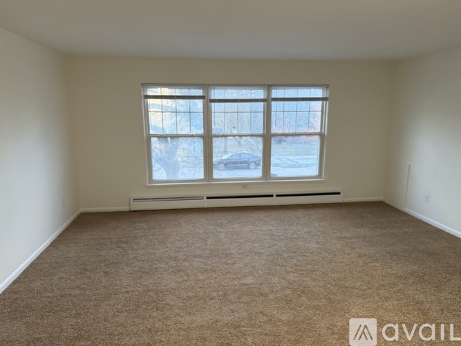 A room with a large window and a carpeted floor.