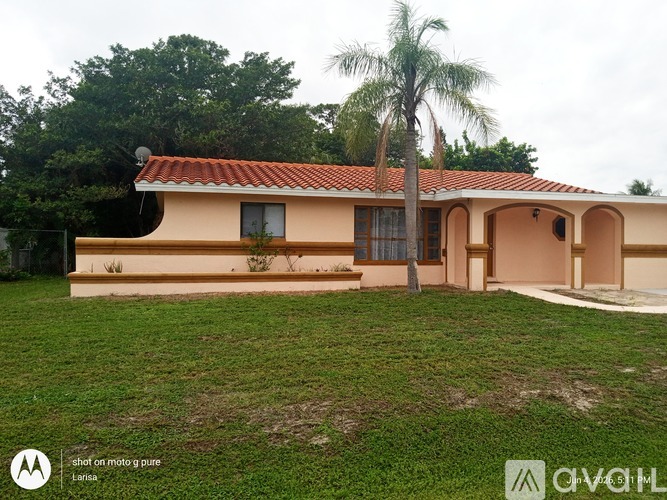 A house with a red tile roof and a palm tree in front.