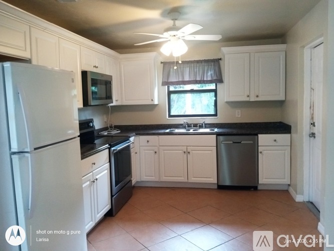 A kitchen with white cabinets and a black countertop.