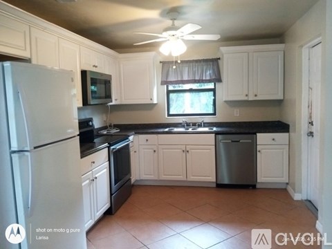 A kitchen with white cabinets and a black countertop.