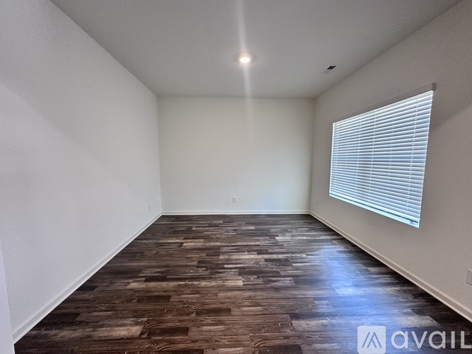 A room with wooden flooring and a window with blinds.