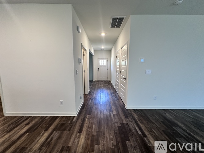 A long hallway with wood flooring and white walls.