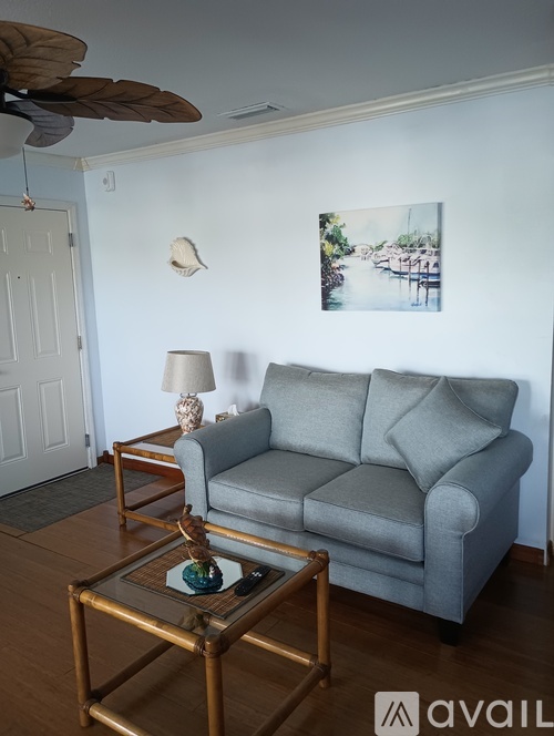 A grey couch with a glass table in front of it.