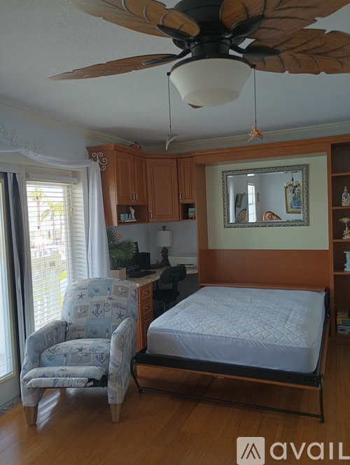 A bedroom with a bed, chair, and a ceiling fan.